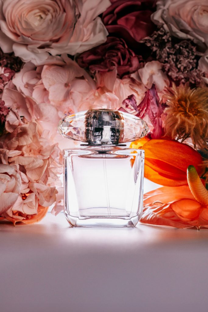 flacon de parfum vide transparent sur fond de fleurs rose et orange
