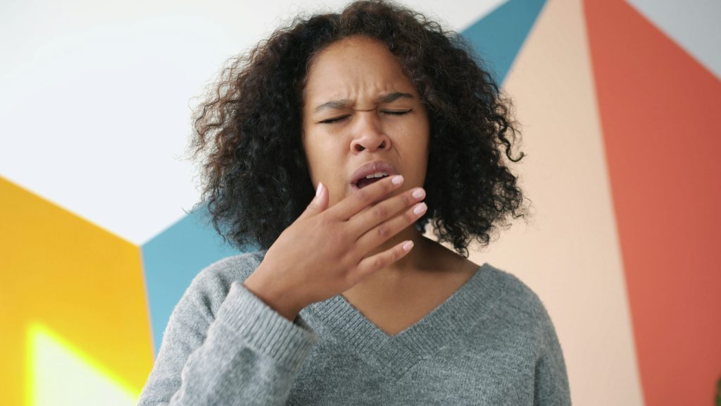 femme qui grimace avec une main devant la bouche
