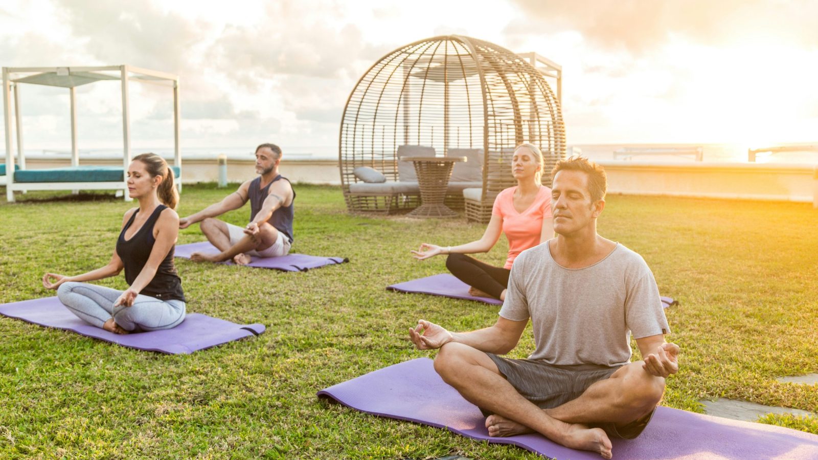 groupe de personnes pratiquant le yoga sur un tapis dans l'herbe